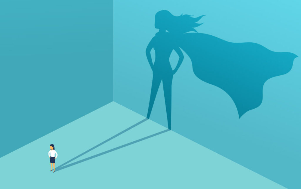 Illustration of a woman in a business skit and blouse standing with her hands on her hips in a teal space with light that hits her from the left and projects a larger shadow of the woman in a super hero cape with her hair flowing.