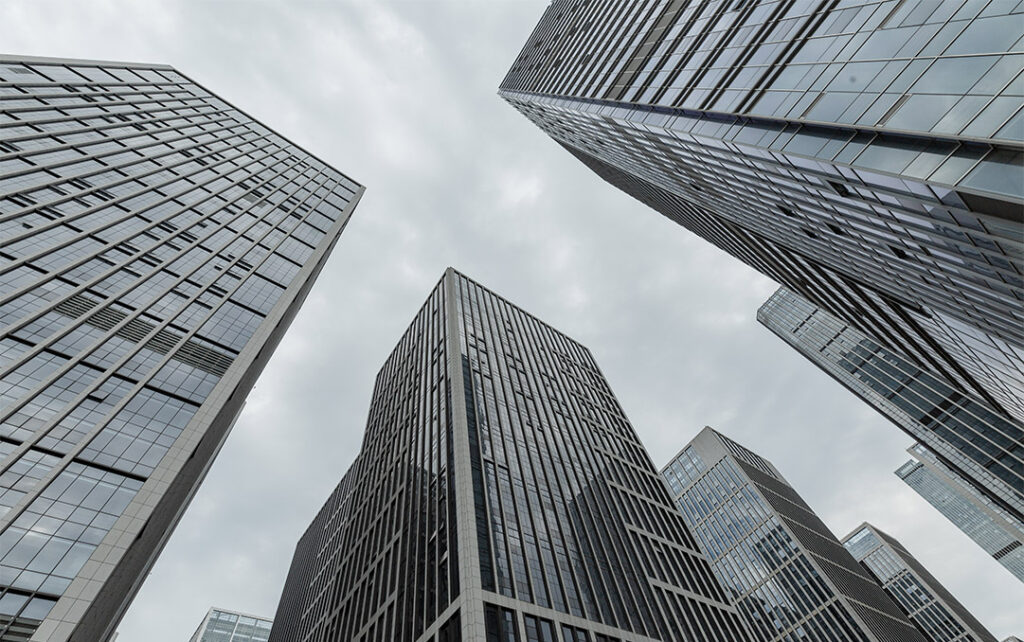 Photograph looking up at the sky in a city with several sky scrapers jutting towards the sky on an overcast day.