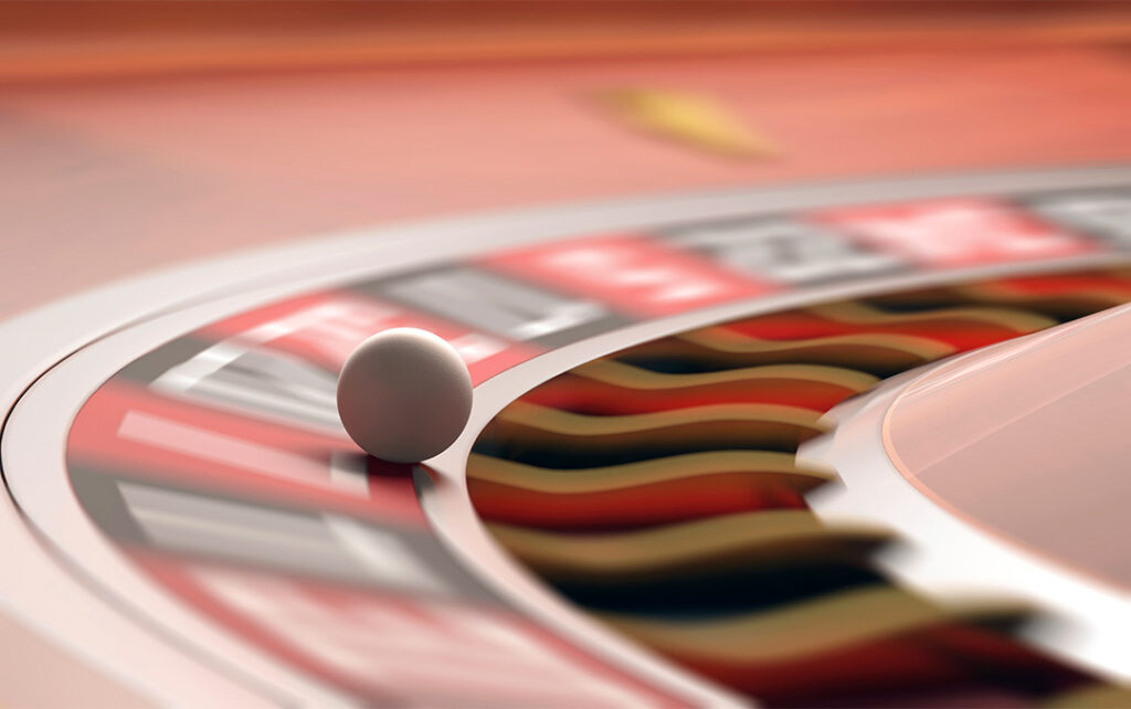 Closeup photograph of a Russian Rulet board with a ball in motion about to land in a slot.