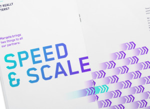 photograph of a closeup of the inside of a MARQETA brochure. We see two cropped with pages, the left side has large teal, blue to purple gradient text that reads in all capital letters, "SPEED & SCALE". The left side of the pamphlet has small gradient purple double motion arrows pointing too the right on the bottom portion of the page.